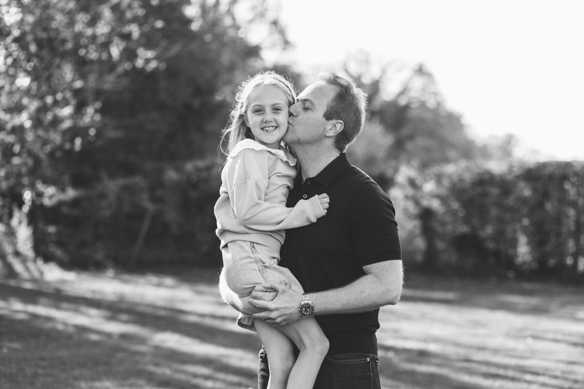 A father kisses his young daughter on the cheek.