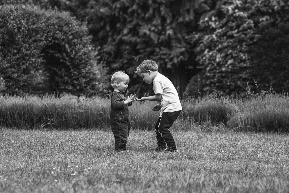 Siblings catch dandelion seeds as they blow across the garden.