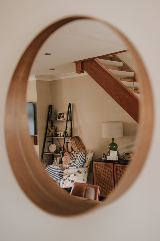 An image of a mirror, reflected in it is a new mother feeding her son.