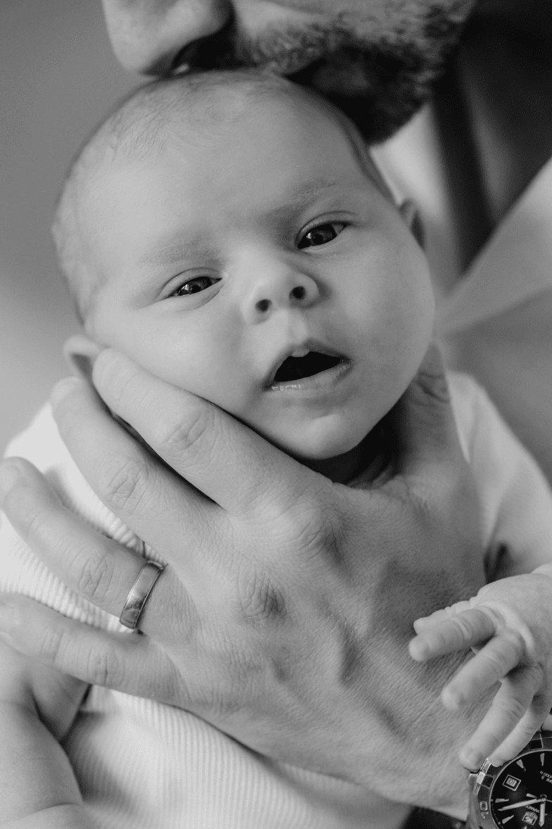 A close crop of a new father kissing his daughter on the head.