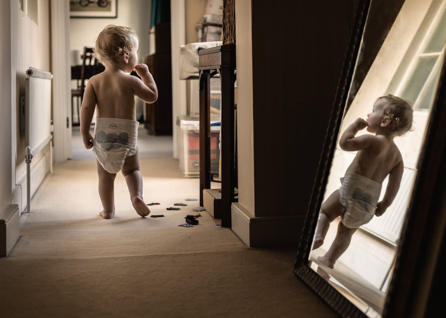 A young boy walks down a corridor at home.