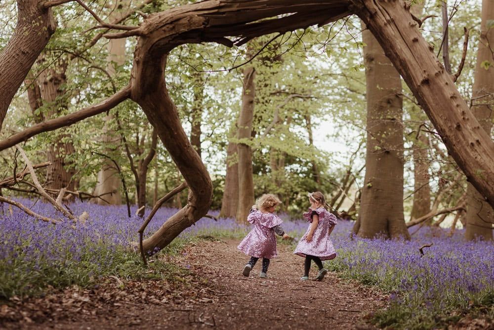 Two young girls twirl on a path between the bluebells in Marlow Common.