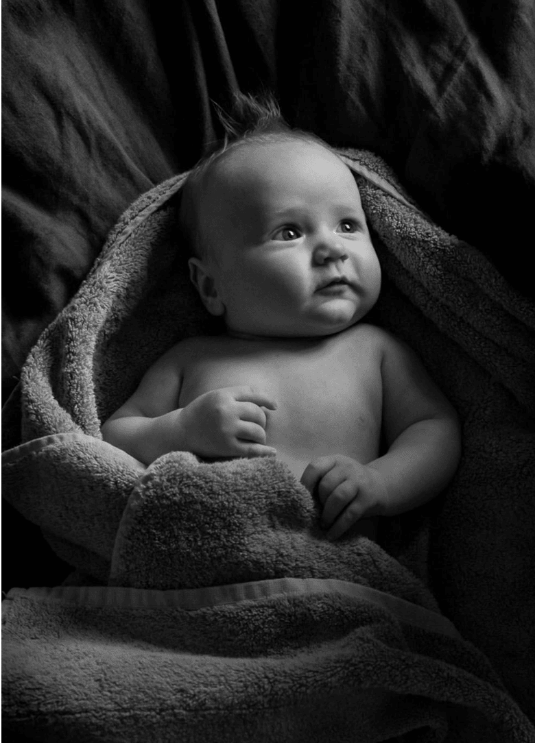 A six-month old baby wrapped in a towel after his bath.