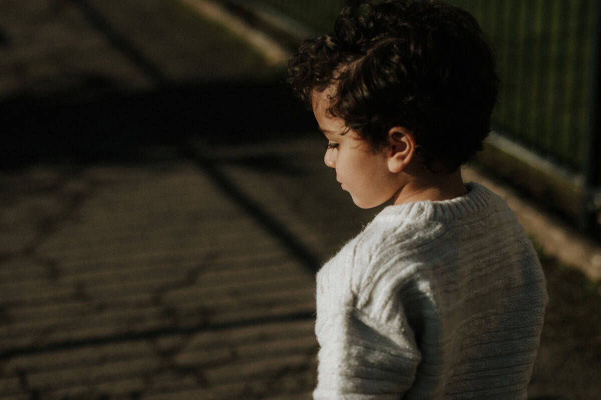 A young boy's face emerges from the shadows on a sunny visit to Higginson Park, Marlow.