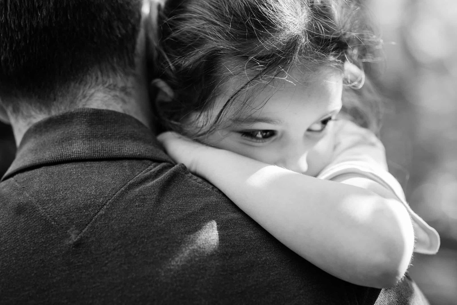 A girl being carried by her father- she leans into his neck.