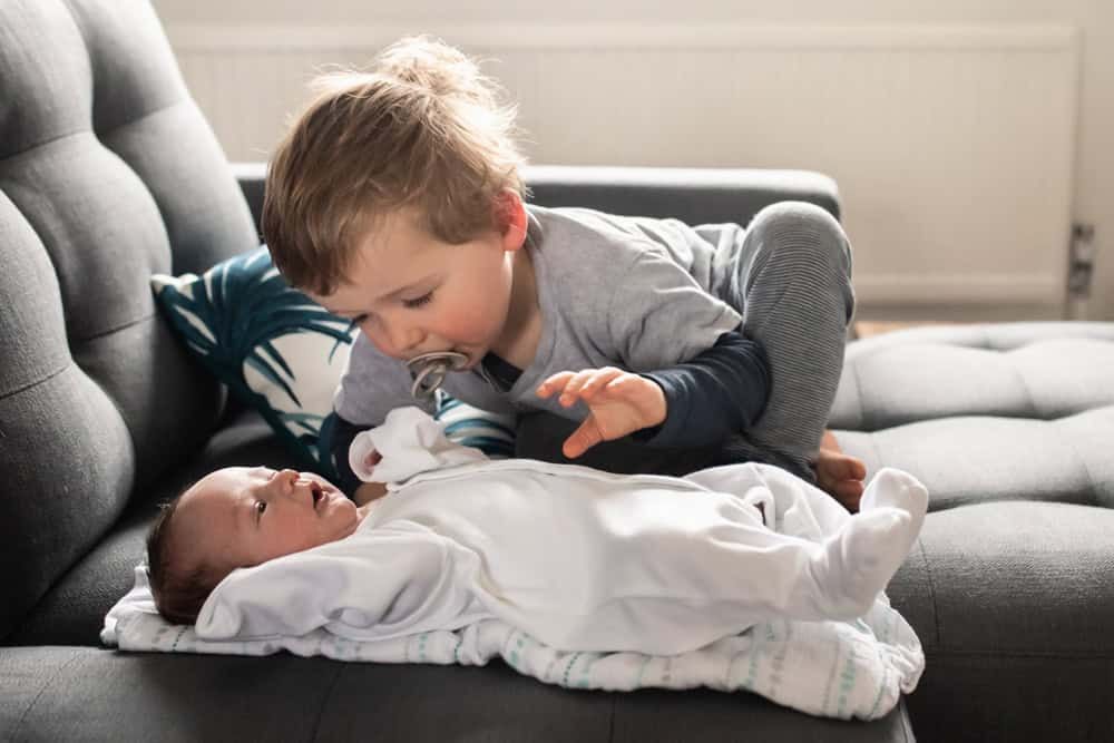 An almost 3-year-old boy plays with his newborn brother.