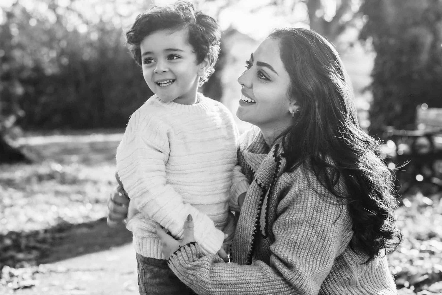 A mother holds hands with her son as they laugh at something the dad is saying.