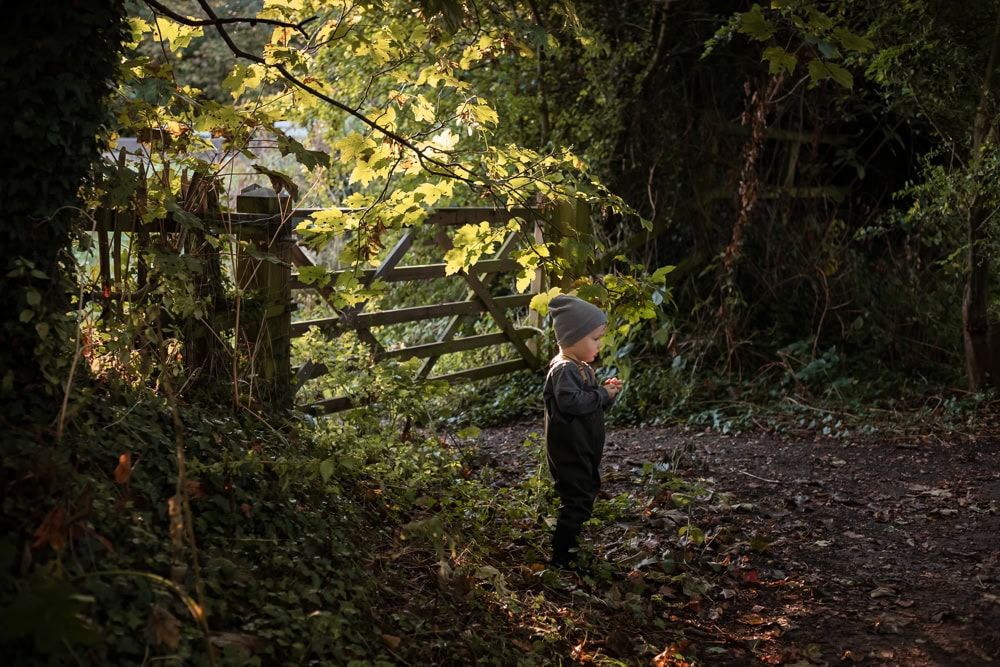 A boy near a gate in beautiful autumn light at Maidenhead riverside.