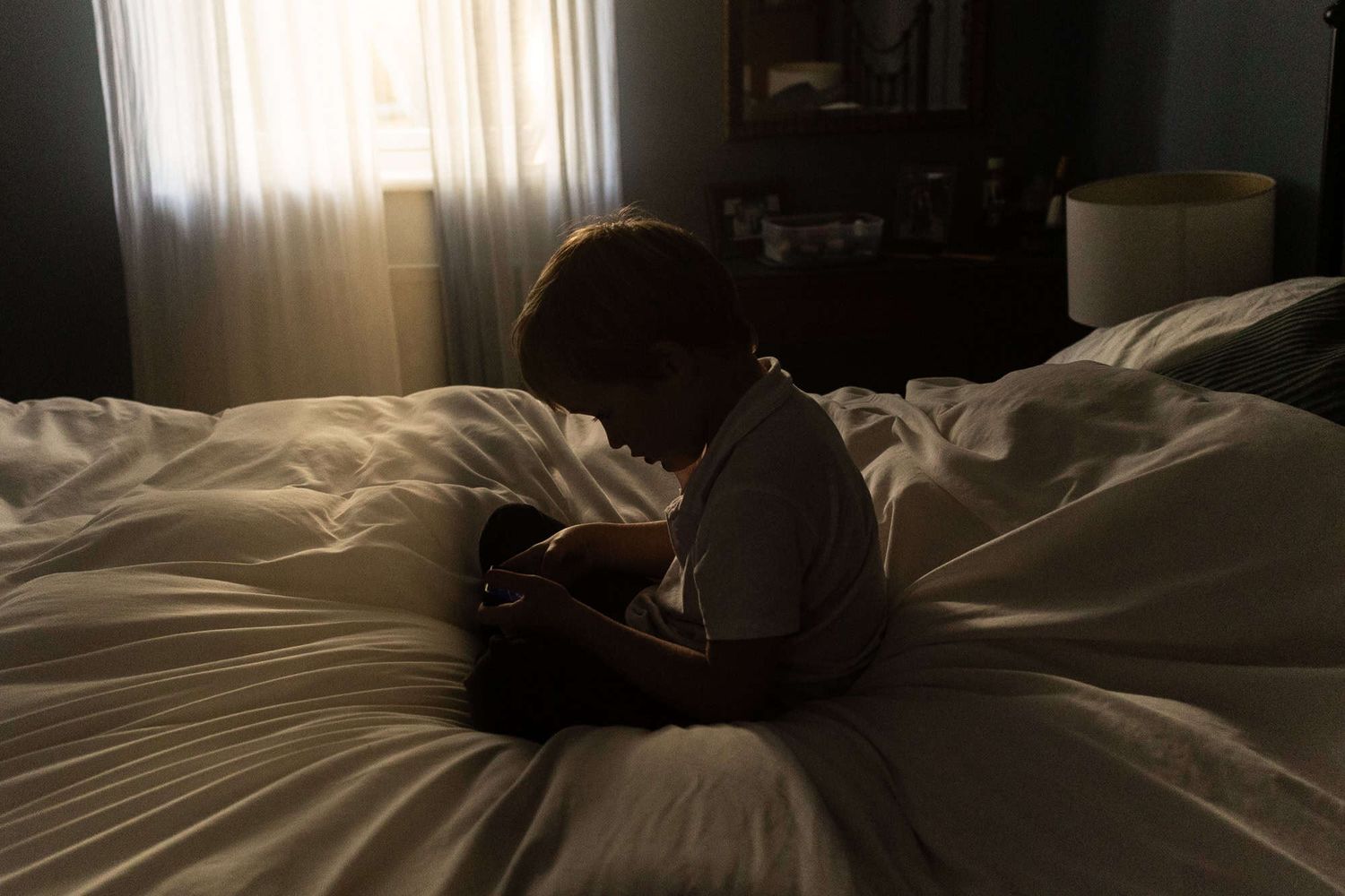 A boy sits reading in the middle of his parents' bed.
