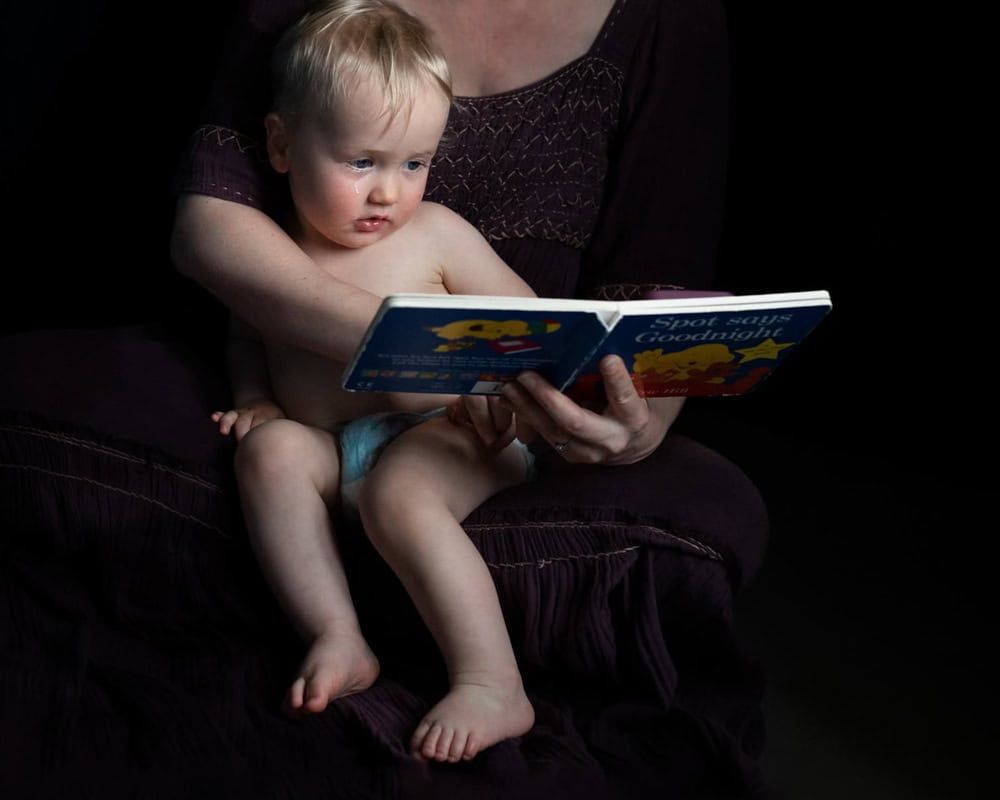 A tear rolls down a toddler's face as a book is read to him.
