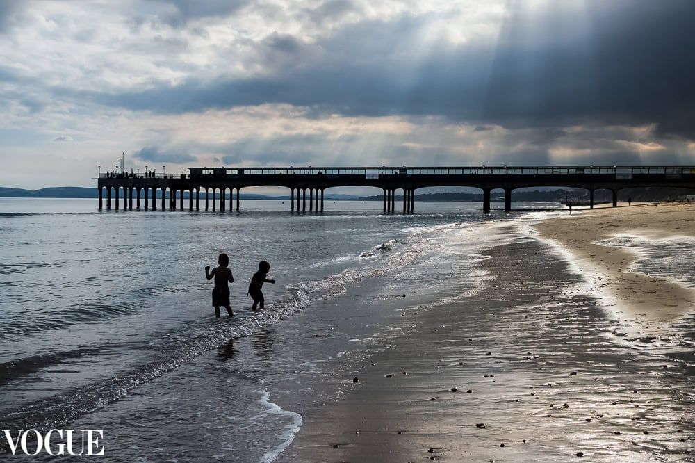 Two children play in the surf at Bournemouth beach under dramatic skies.
