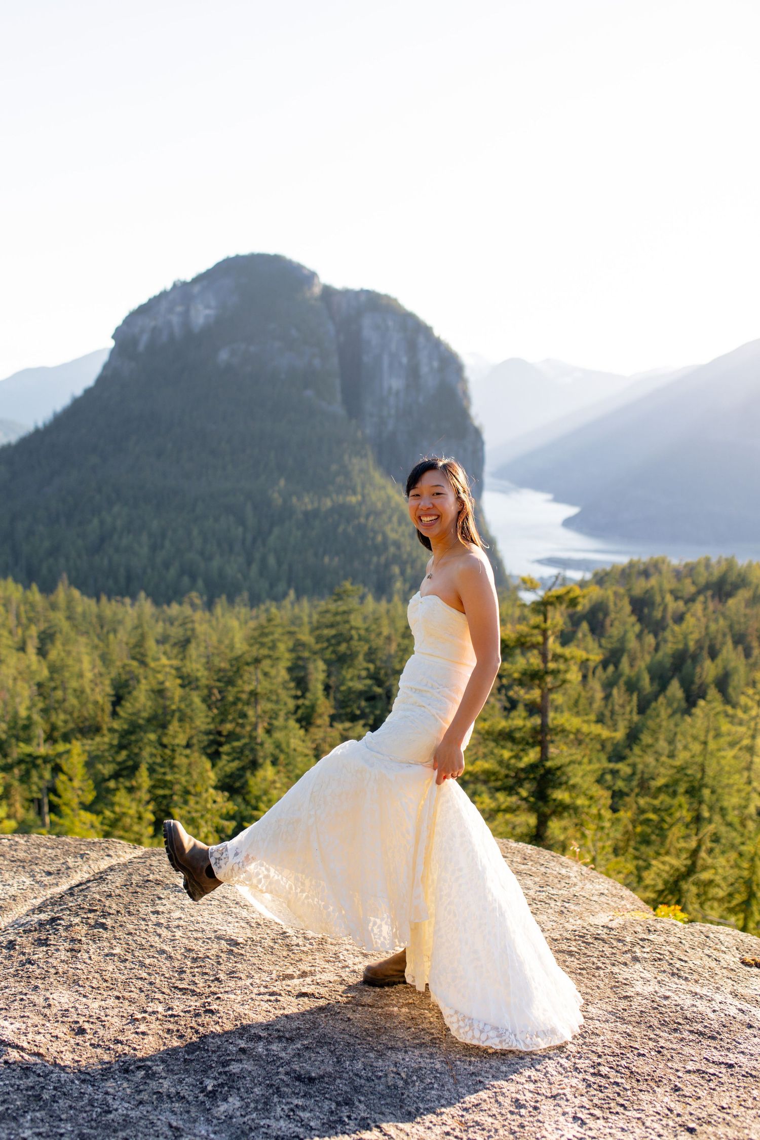 Bride walking along mountain ridge in Squamish with Stawamus Chief in the background at sunset.