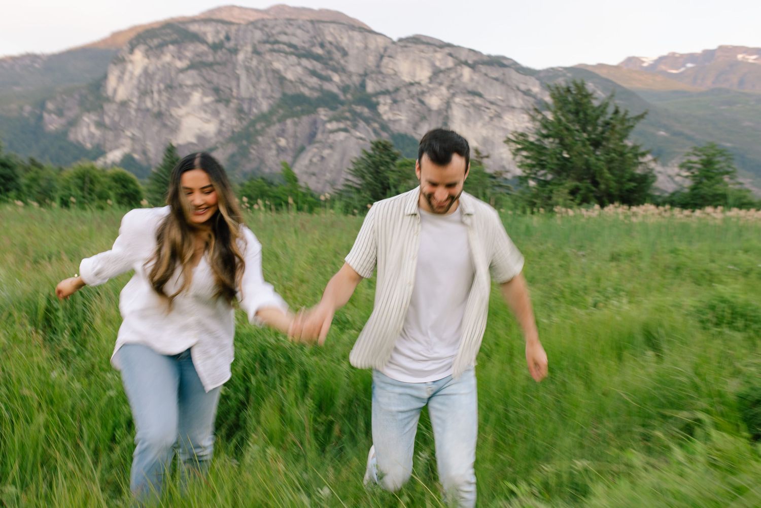 Couple running through grassy meadow in Squamish.