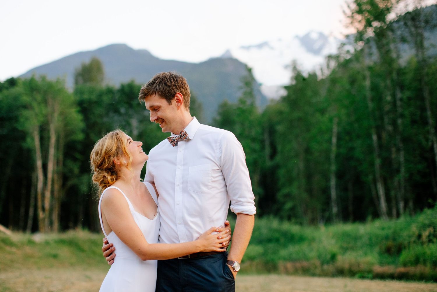 Wedding couple gazing into each other's eyes in front of mountain.