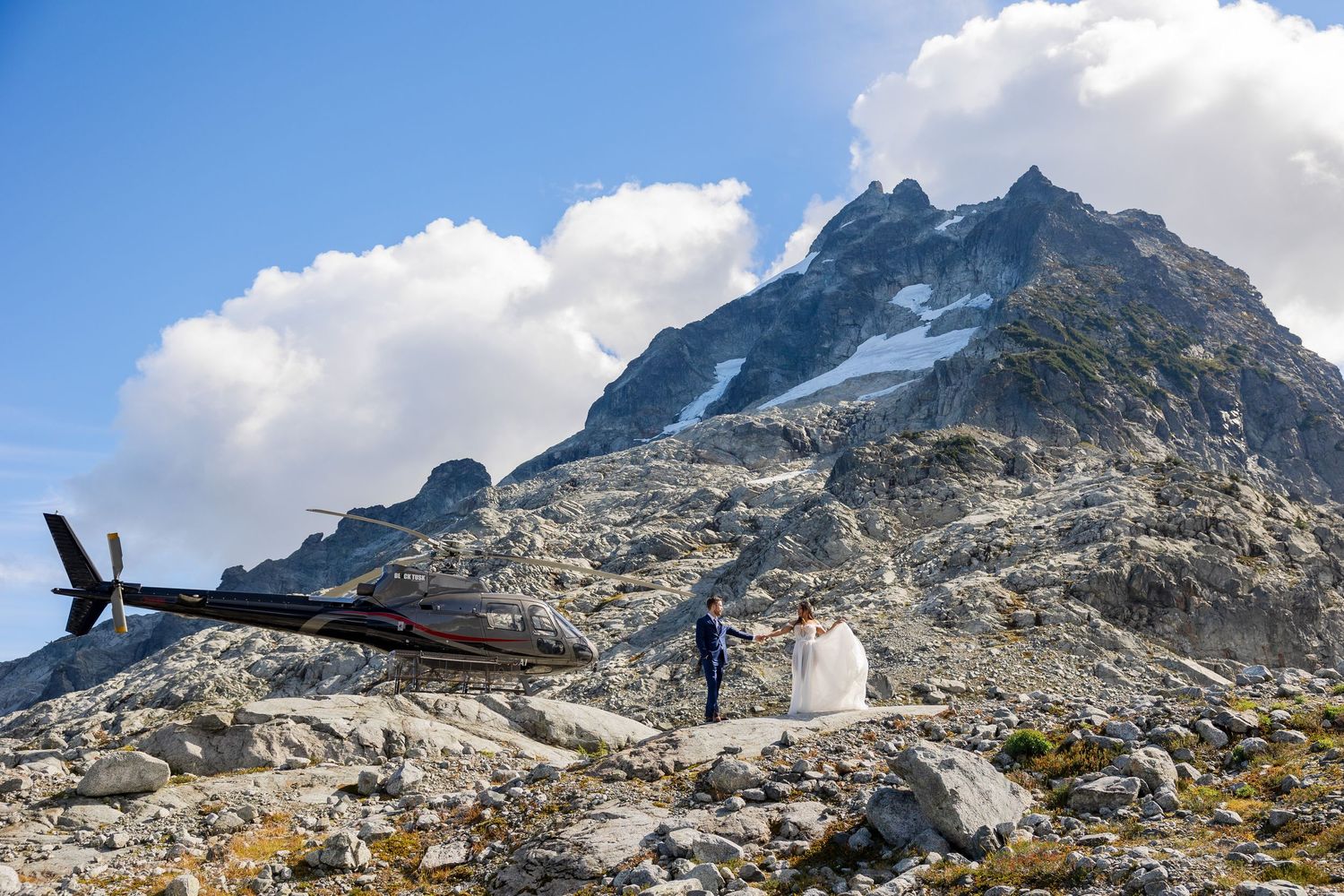Bride hiking in alpine terrain with mountain backdrop.
