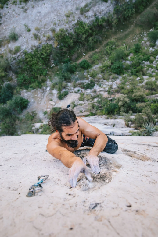 Rock climber chalking hands on granite boulder.