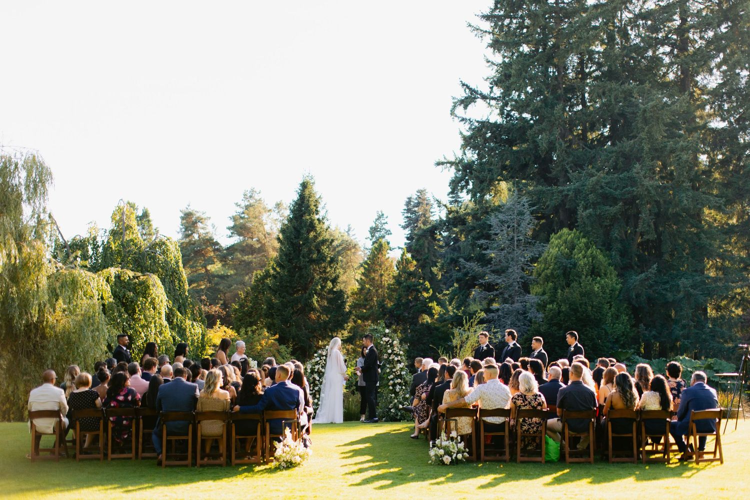 Large outdoor wedding gathering on grassy estate.