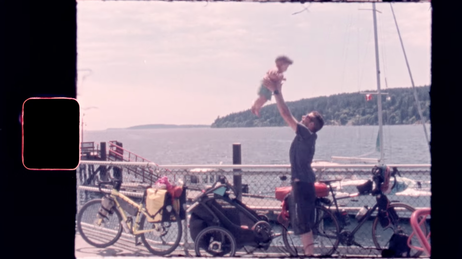 Super 8 wedding film still of couple celebrating near waterfront with vintage film texture.