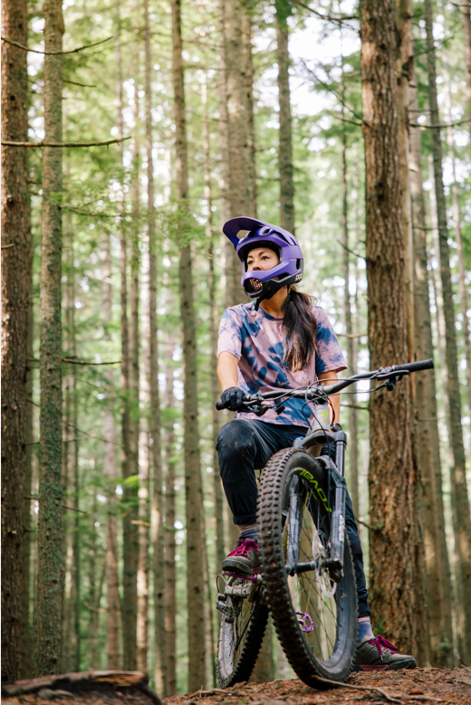 Mountain biker riding through forest trail.