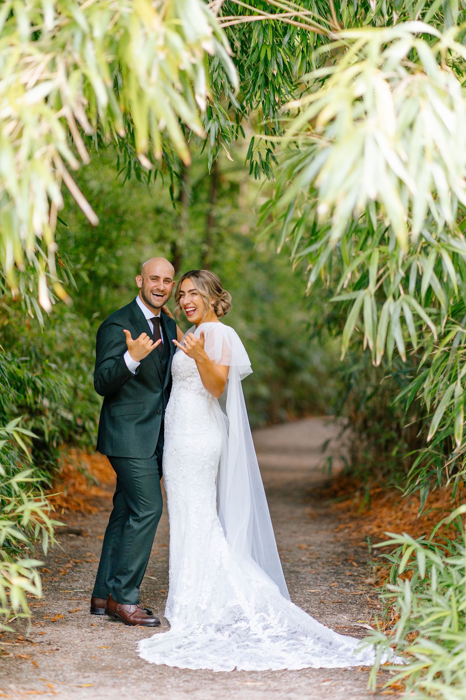 Bride and groom framed by lush garden greenery.