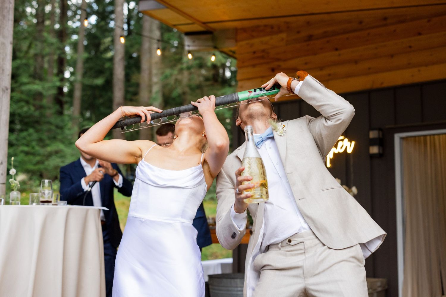 Bride and groom dancing during outdoor wedding reception under timber pavilion.