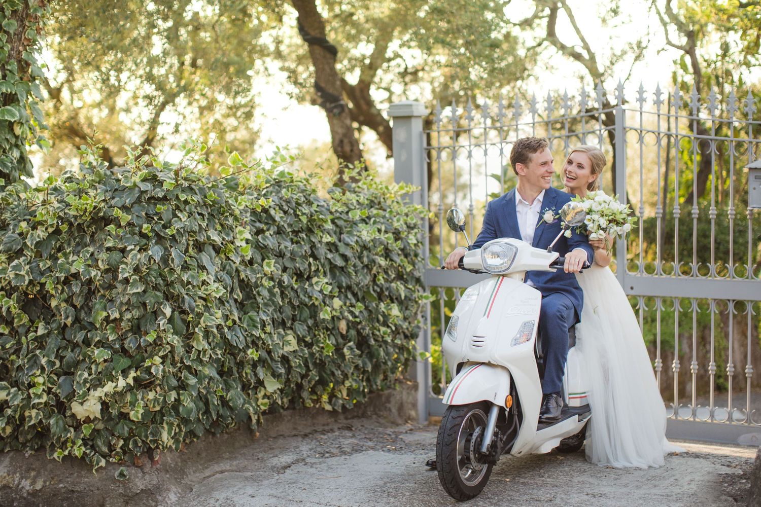 Couple riding vintage scooter after wedding ceremony.