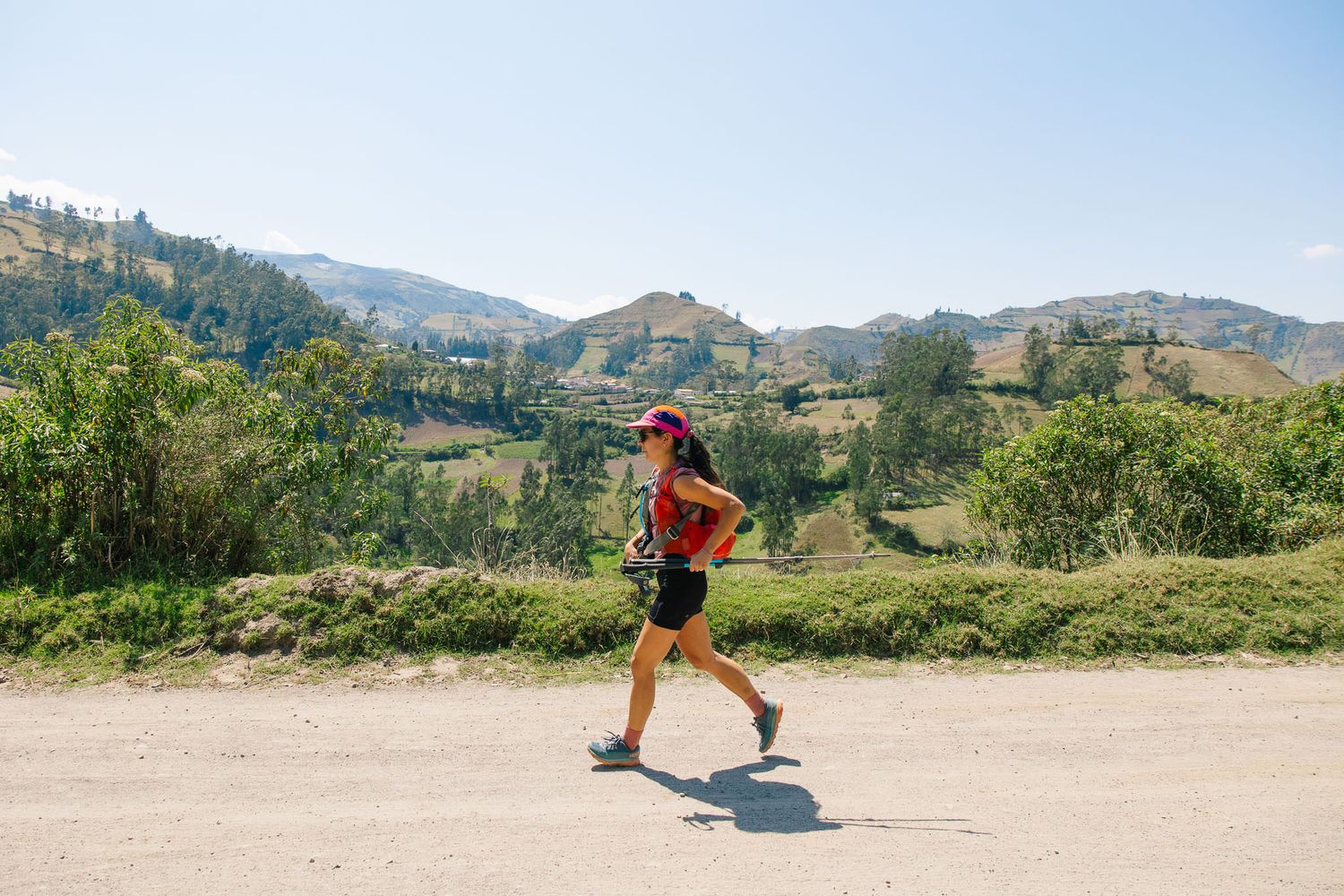 Trail runner moving through sunny hillside landscape.