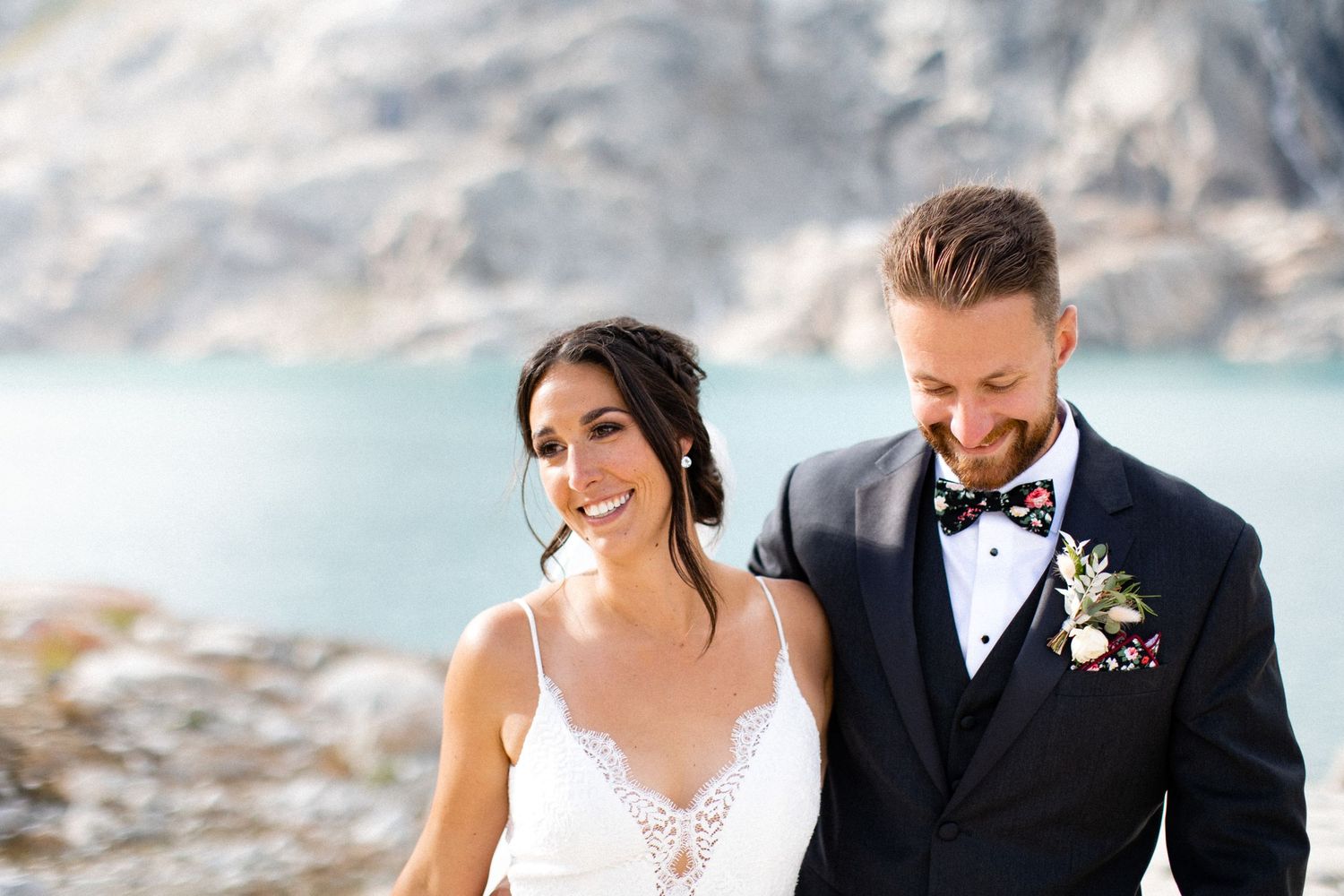 Bride and groom walking together in alpine landscape.