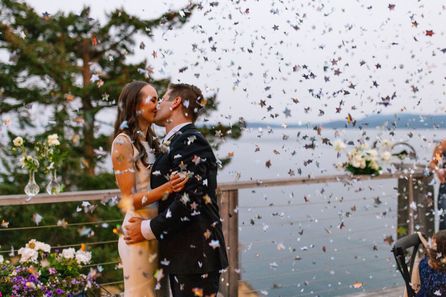 Couple celebrating with confetti outside coastal venue.