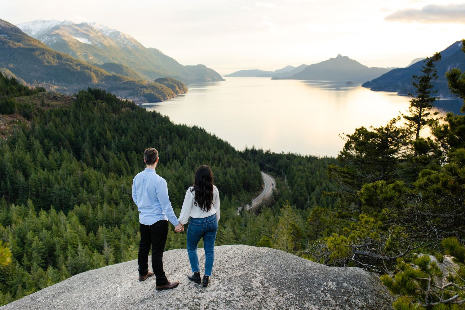 Couple standing on viewpoint overlooking sea of clouds.