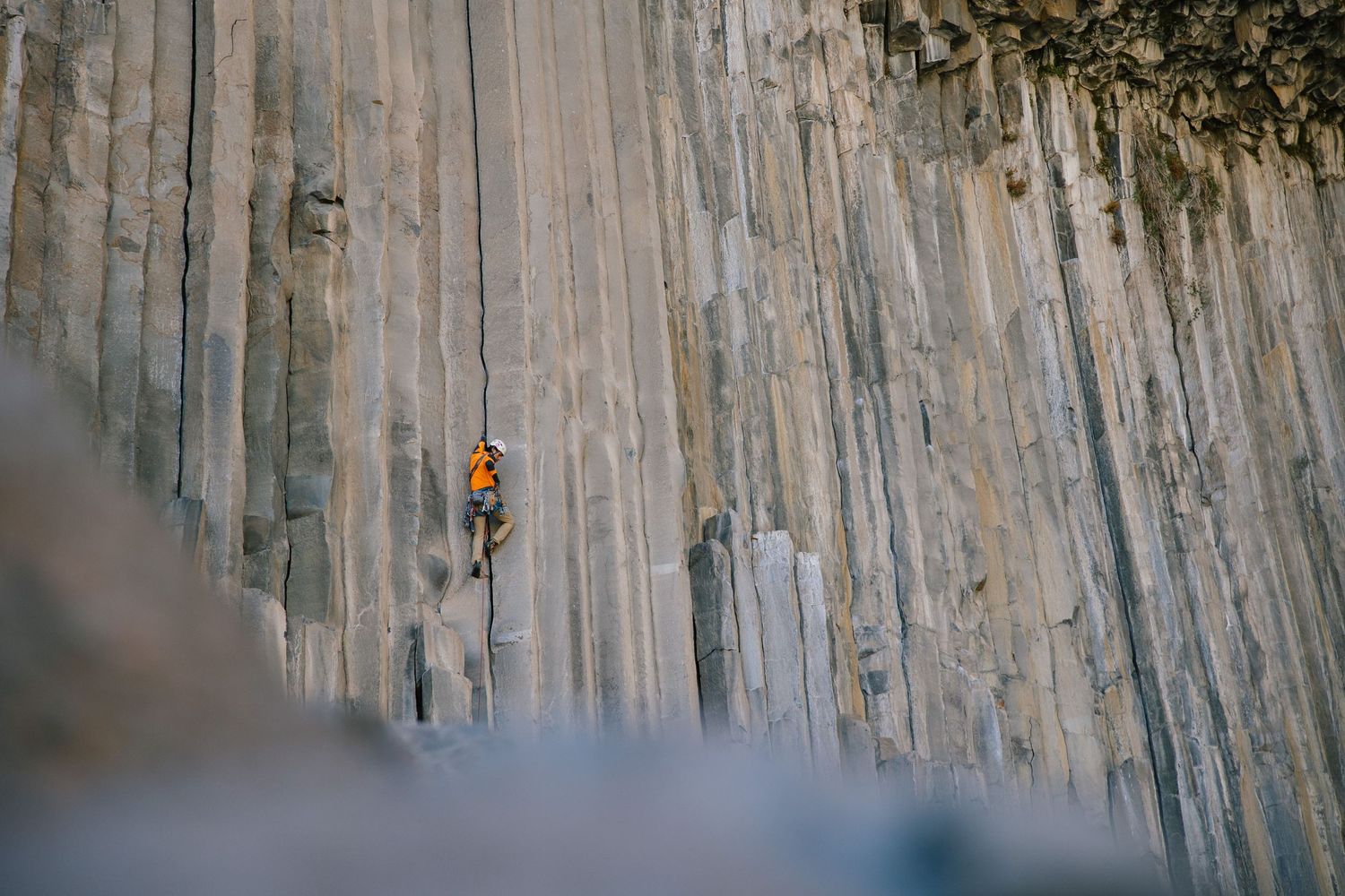 Sport climber ascending vertical rock wall outdoors.