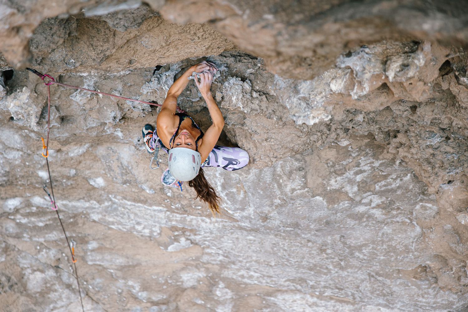 Rock climber navigating textured limestone cliff face.