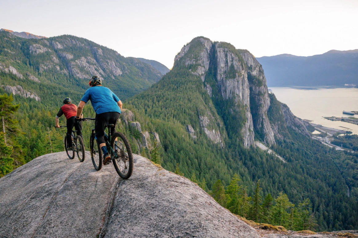Mountain biker overlooking coastal mountains and ocean in Squamish.