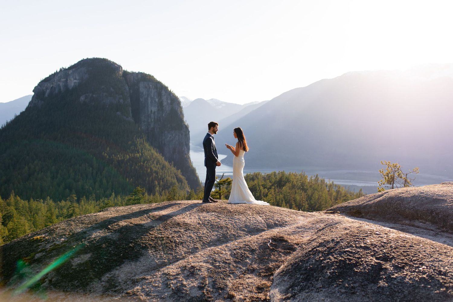 Bride and groom standing together on rocky viewpoint overlooking Howe Sound in Squamish.