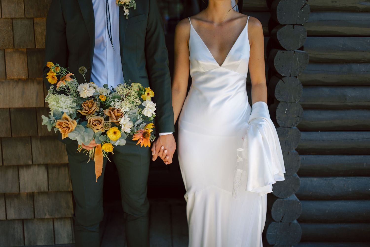 Bride holding bouquet in front of textured wall.