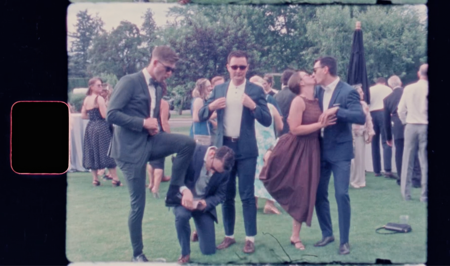 Super 8 wedding film moment of wedding party running and cheering outdoors.