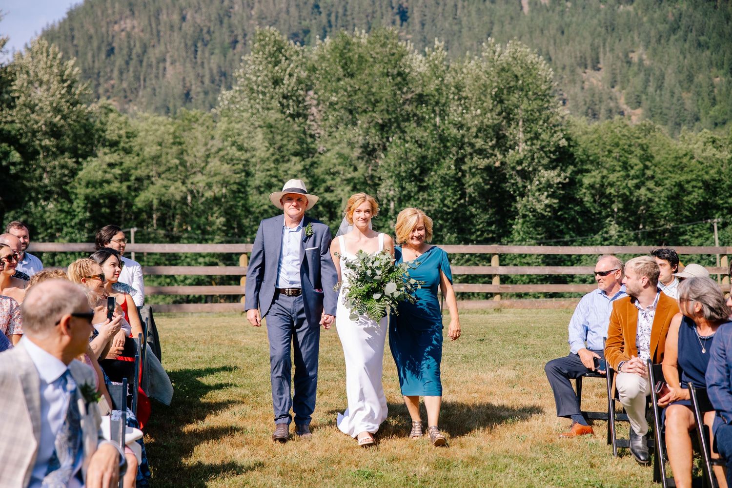 Bride walking down the aisle with parents at Glacier Valley Farm wedding in Squamish, BC.