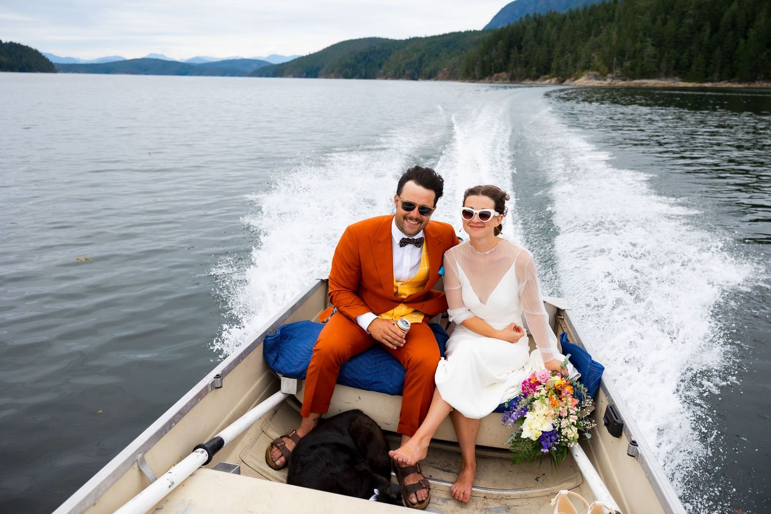 Couple riding in small boat on calm coastal waters.