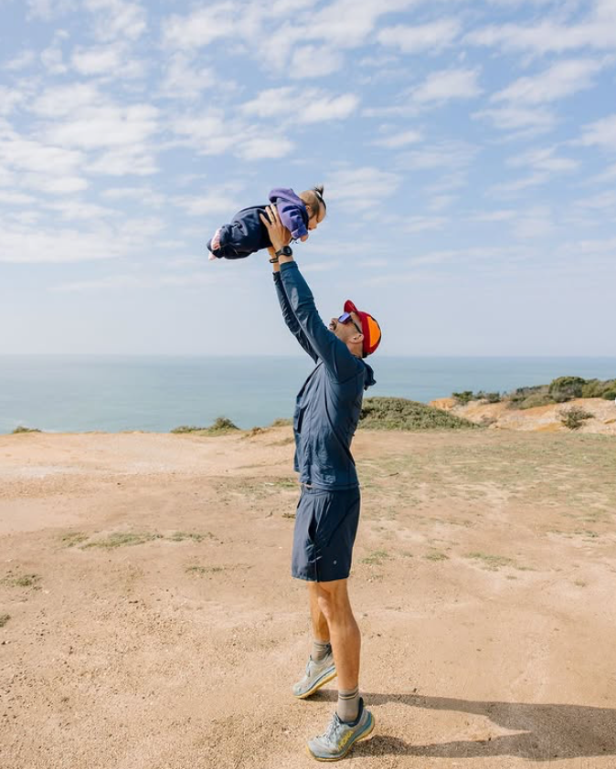 Father holding up his small baby on a cliffside beach in Portugal.