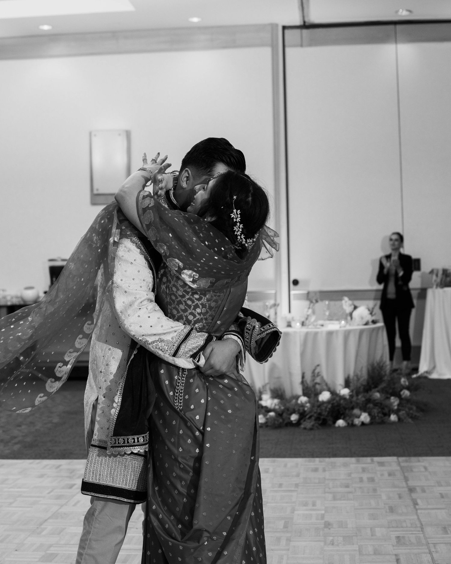 Black and white photo of a couple sharing an emotional embrace during their South Asian wedding reception.
