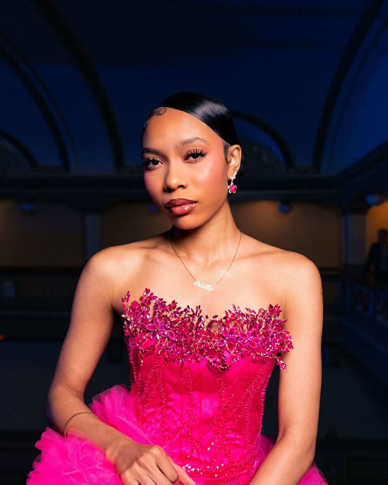 Young woman in a stunning hot pink strapless beaded ball gown posing elegantly at a formal event.