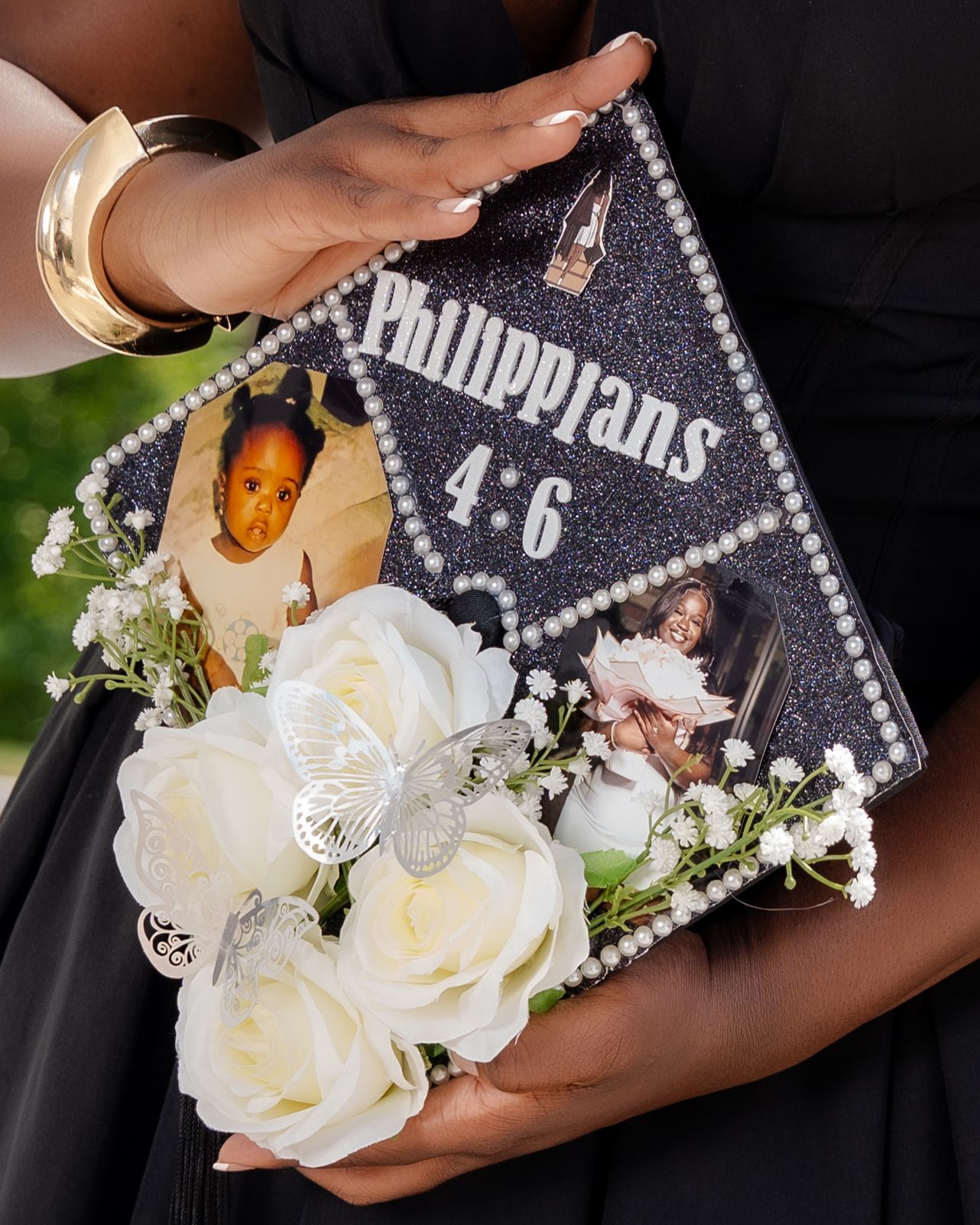 Decorated graduation cap with Philippians 4:6, pearl trim, white roses, butterfly, and cherished family photos.