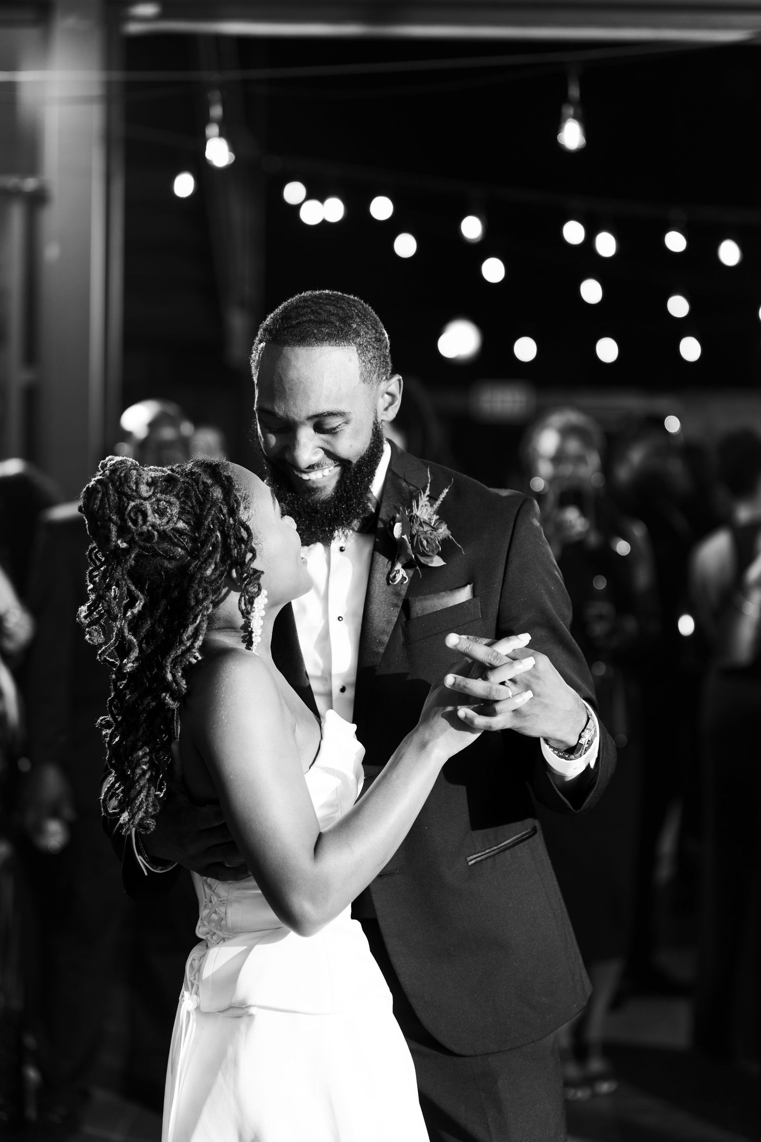 Black and white photo of a bride and groom sharing their first dance at a wedding reception.