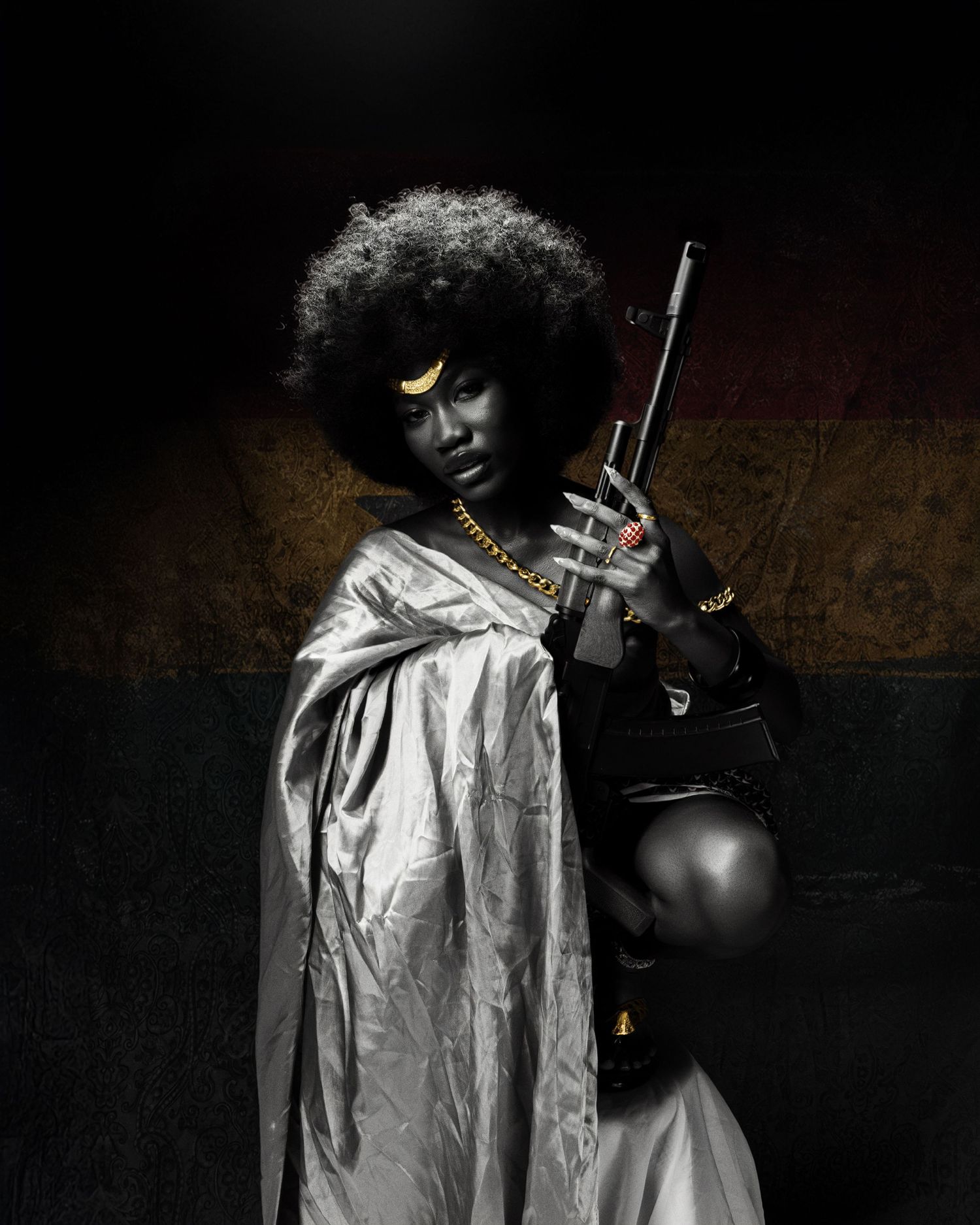 A dramatic portrait of a woman with an afro, silver cape, gold jewelry, and a rifle in a dark studio setting.