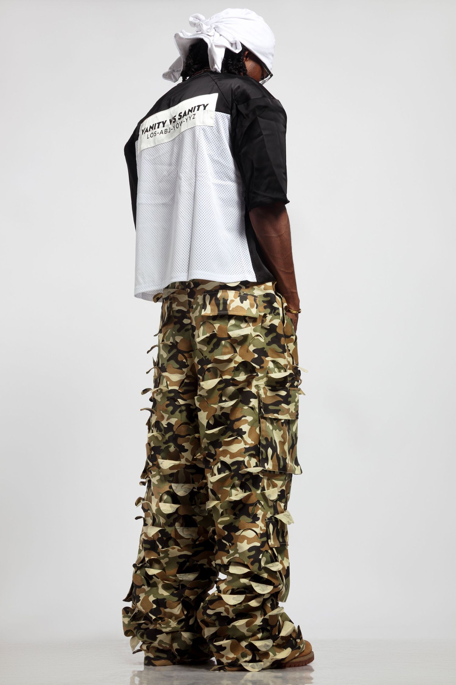 Back view of person wearing black and white shirt with camo cargo pants.
