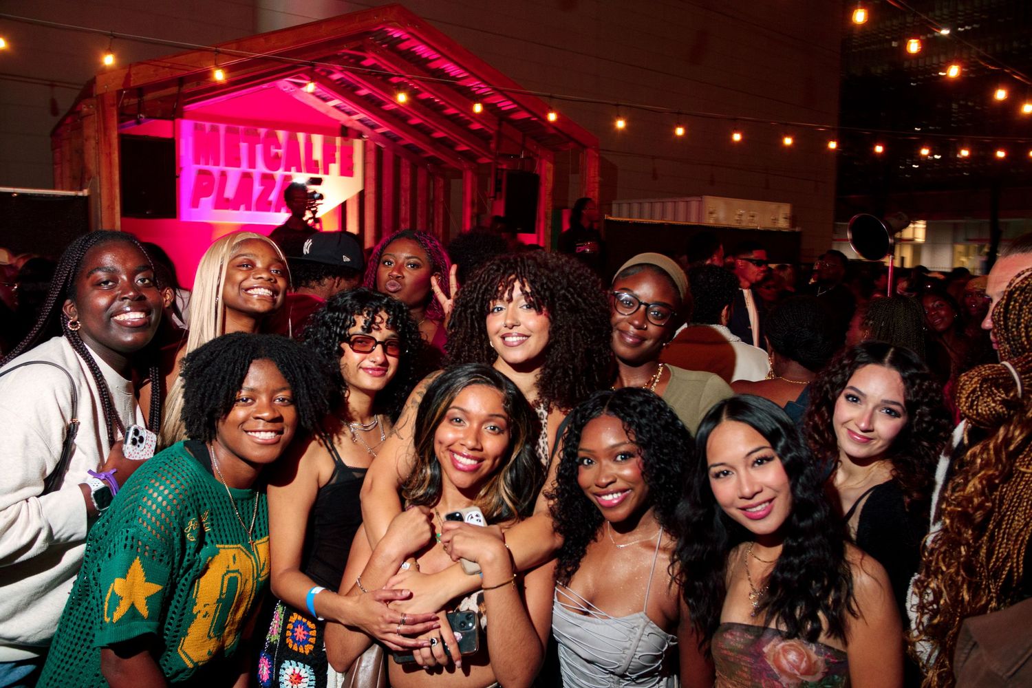 Lively nightclub crowd enjoying a party under pink and red lighting.