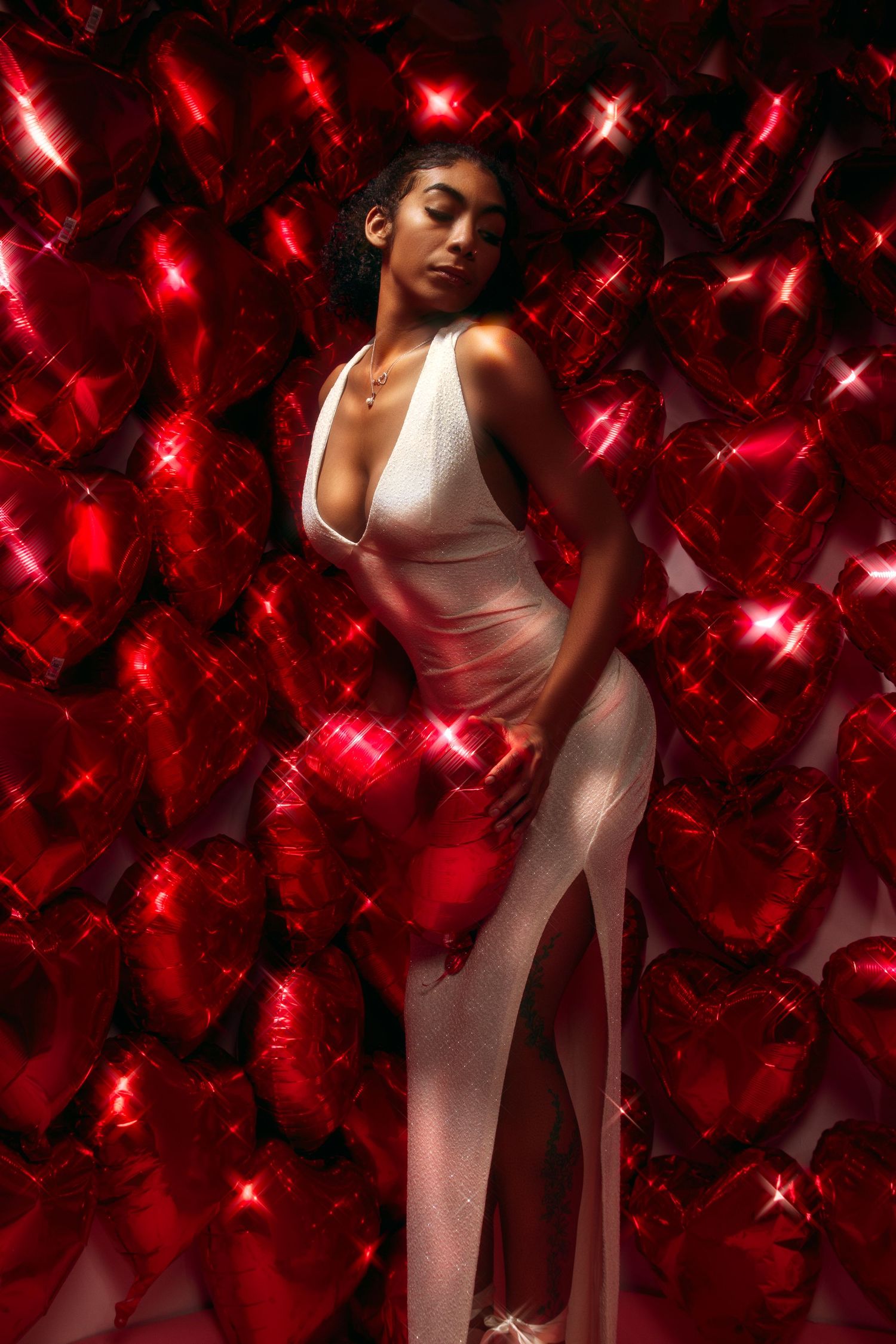 Artistic portrait against red sparkly background with dramatic lighting and white dress.