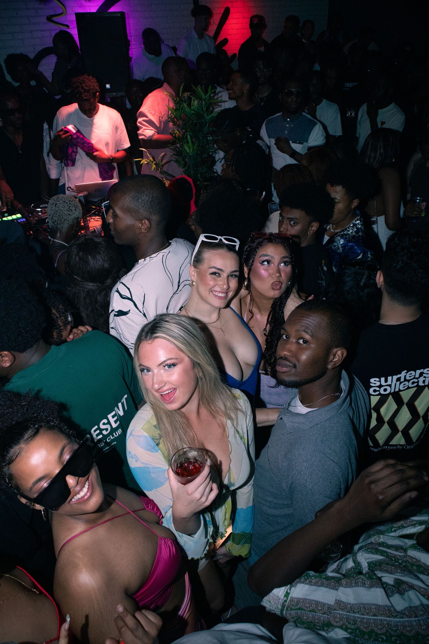 Energetic crowd enjoying music at a nightclub under colorful lighting.