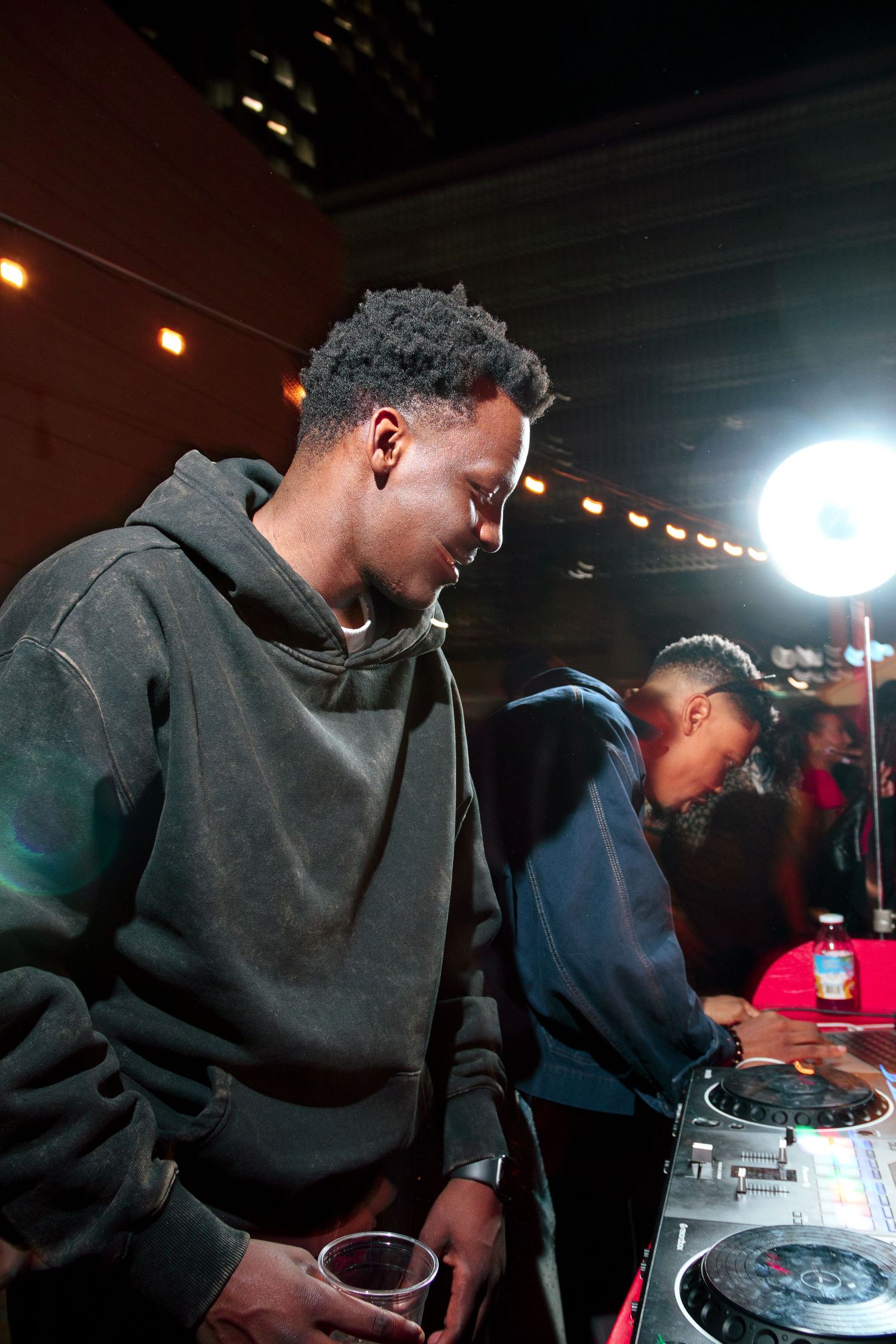 DJs working the turntables in dark lighting at a club event.