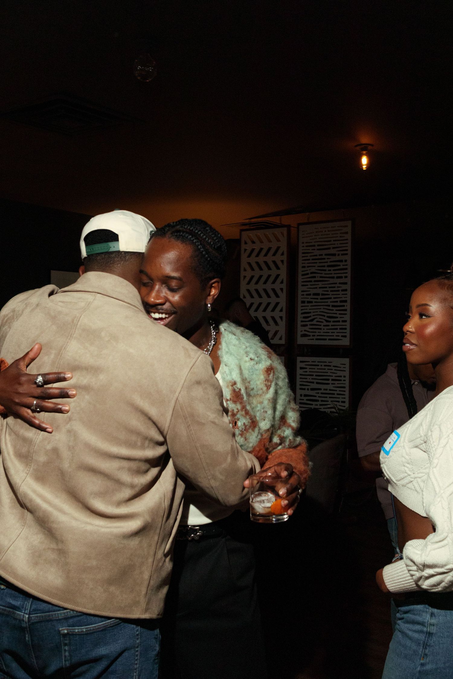 Group of people embracing in a dimly lit room showing warmth and connection.